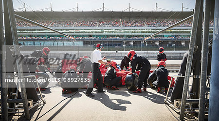 Manager and pit crew replacing tires on formula one race car in pit lane Manager and pit crew replacing tires on formula one race car in pit lane