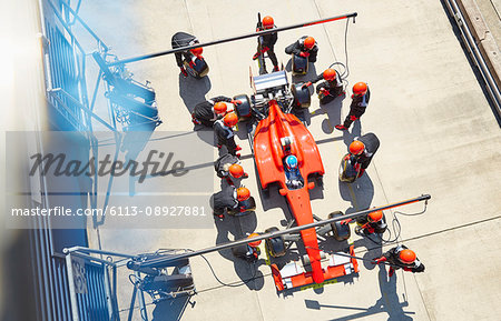 Overhead pit crew replacing tires on formula one race car in pit lane