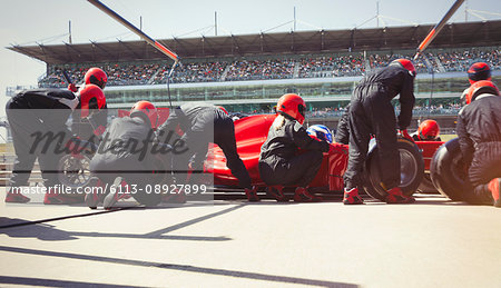 Pit crew replacing tires on formula one race car in pit lane