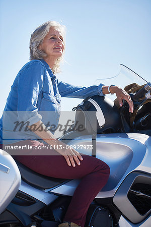 Smiling senior woman sitting on motorcycle, looking away