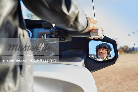 View of senior man in side-view mirror riding motorcycle