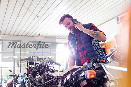 Motorcycle mechanic talking on cell phone in workshop