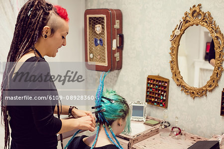Beautician styling clients hair in dreadlocks shop