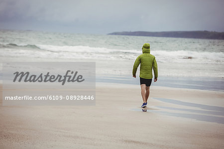 Rear view of athlete running on the beach