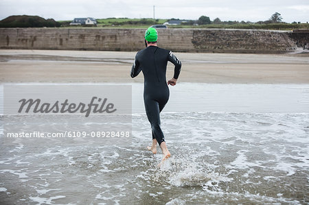 Rear view of athlete running towards the beach