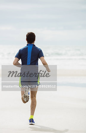 Rear view of athlete running on the beach