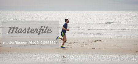 Handsome athlete running along the beach