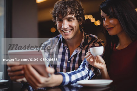 Couple using digital while having coffee in restaurant