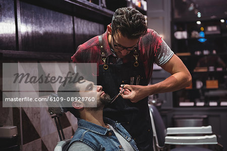 Man getting his beard trimmed with scissor in barber shop