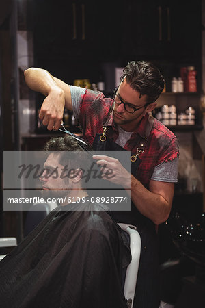 Man getting his hair trimmed with scissor in barber shop