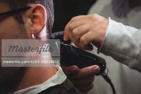 Close-up of man getting his hair trimmed with trimmer in barber shop