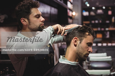 Hairdresser combing clients hair in barber shop