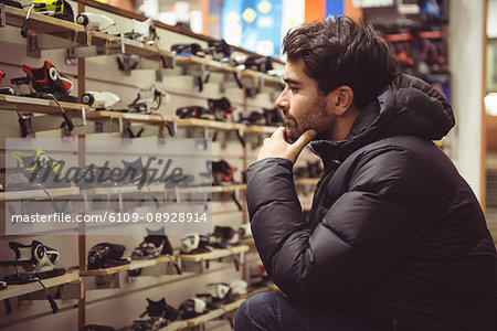Handsome man selecting ski binding in a shop