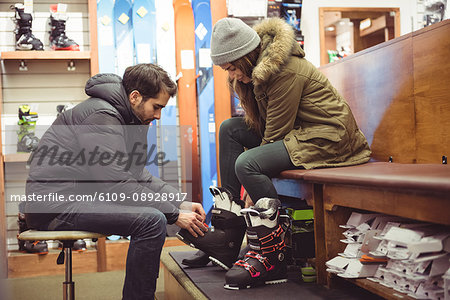 Man helping woman to wear ski boot in a shop