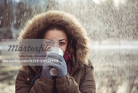 Portrait of a beautiful woman in fur coat drinking coffee in winter