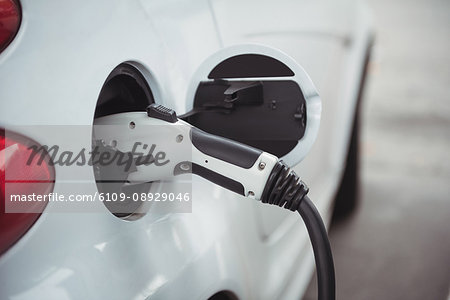 Close-up of car being charged with electric car charger at charging station