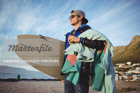 Man carrying surfboard standing on beach
