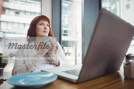 Pregnant businesswoman having coffee in office cafeteria