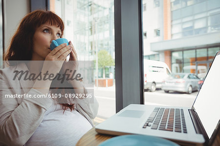Pregnant businesswoman having coffee in office cafeteria