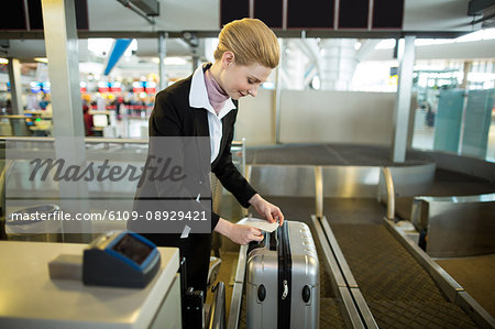 Airline check-in attendant sticking tag to the luggage of commuter at airport
