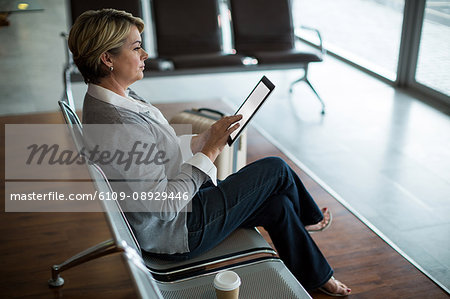 Businesswoman using digital tablet in waiting area at airport terminal