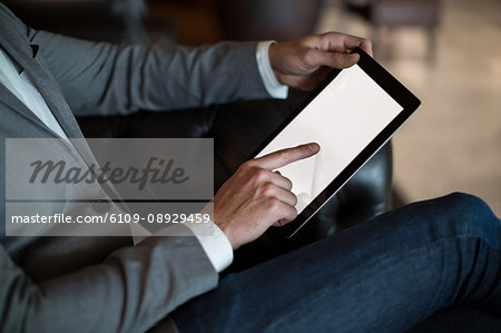 Mid section of businessman using digital tablet in waiting area at airport terminal