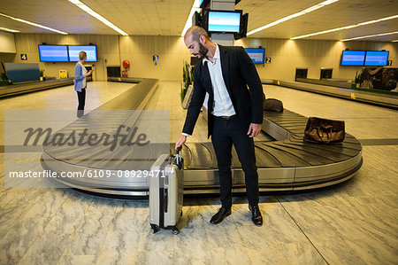 Businessman with trolley bag in waiting area at airport terminal