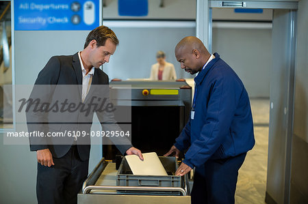 Airport security officer checking package of passenger in airport