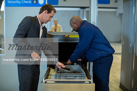 Airport security officer checking luggage of commuter in airport terminal