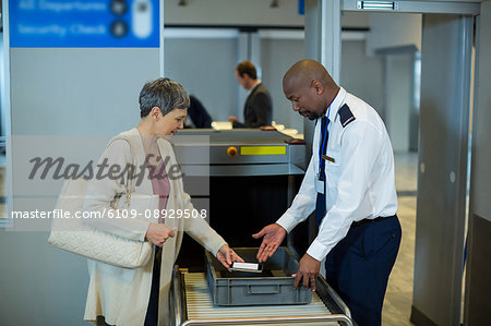 Airport security officer checking commuter mobile phone in airport terminal