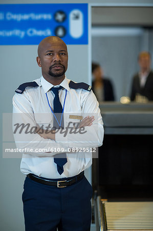 Portrait of airport security officer standing with arms crossed in airport terminal