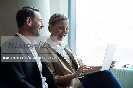 Businesspeople discussing over laptop at airport