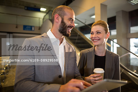 Businesspeople discussing over digital tablet at airport