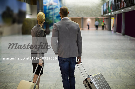 Rear view of businesspeople with luggage at airport terminal