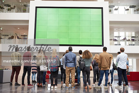 Students looking up at a big screen in university building