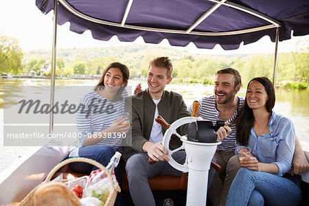 Group Of Friends Enjoying Day Out In Boat On River Together