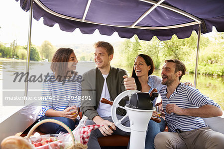 Group Of Friends Enjoying Day Out In Boat On River Together