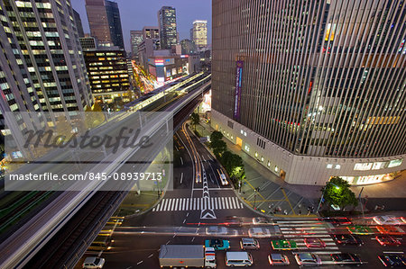 A wide-angle view and a slow shutter speed capture a Shinkansen bullet train streaking past the Yurakucho Mullion Building, crossing Daimyyokoji Avenue and Harumi Dori Avenue, and cutting right through the middle of the Yurakucho District at twilight in central Tokyo, Japan. A wide-angle view and a slow shutter speed capture a Shinkansen bullet train streaking past the Yurakucho Mullion Building, crossing Daimyyokoji Avenue and Harumi Dori Avenue, and cutting right through the middle of the Yurakucho District at twilight in central Tokyo, Japan.