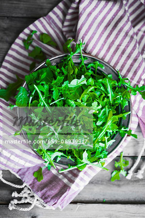 A bowl of rocket on a striped cloth