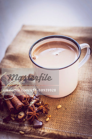 A mug of hot chocolate on a piece of jute with Christmas spices