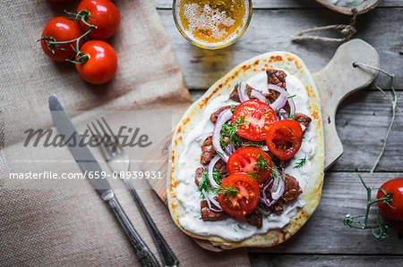 Pitta bread topped with beef, cream cheese, tomatoes and onions