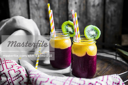 Two layer smoothies with straws in screw-top jars