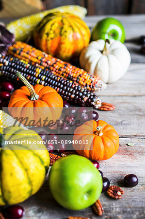 Pumpkins, corn cobs, apples, nuts and cranberries on a wooden surface Pumpkins, corn cobs, apples, nuts and cranberries on a wooden surface