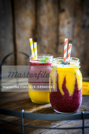 Colourful two layer mango and berry smoothies garnished with blackberries Colourful two layer mango and berry smoothies garnished with blackberries