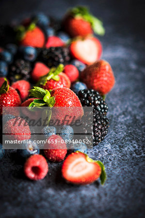 Various berries on a rustic black surface Various berries on a rustic black surface