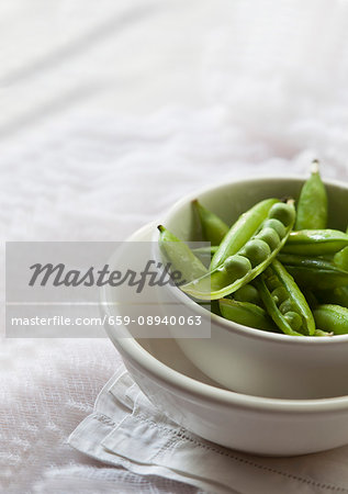 Fresh peas in pods in a white bowl