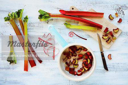 Rhubarb spears, whole and sliced, on a wooden board and in a pot Rhubarb spears, whole and sliced, on a wooden board and in a pot
