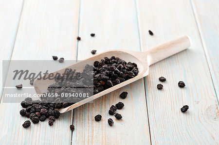 Dried aronia berries on a wooden scoop