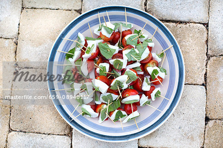 Tomato and mozzarella skewers with basil on a plate