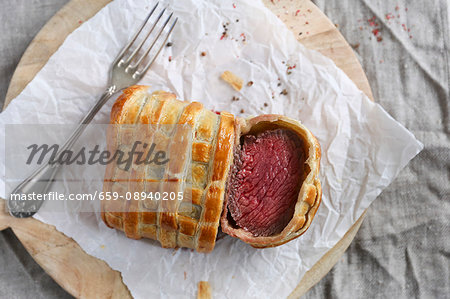 Beef Wellington, sliced, on a piece of paper (seen from above)